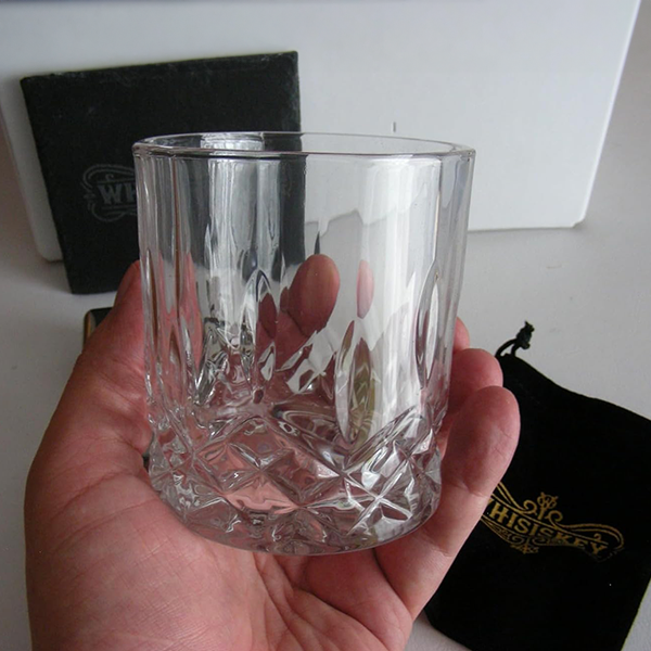 glass_whiskey_tumbler_in_hand_with_coaster_in_background
