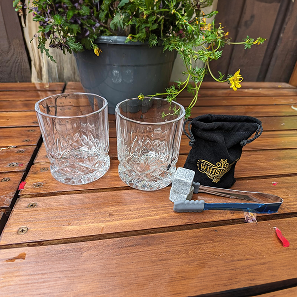 two_whiskey_tubmlers_with_granite_cooling_stones_on_table_from_whisiskey