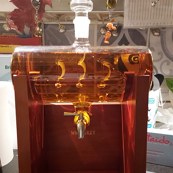 whiskey_decanter_with_sailing_ship_inside_and_pourer_on_wooden_stand